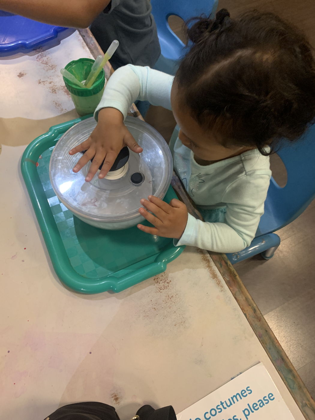 A child spinning a bowl to splatter paint